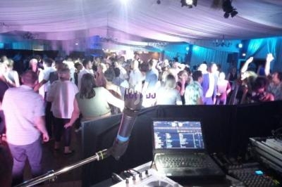 Vue depuis une table de mixage sur une piste de danse animée dans une salle éclairée par des lumières colorées.