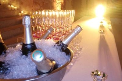 Seau rempli de bouteilles de champagne sur glace, aligné avec des verres à pied dans une salle éclairée.