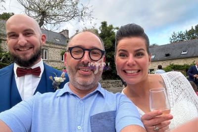Trois personnes souriantes posent pour une photo en extérieur devant des bâtiments en pierre.