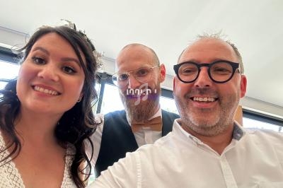 Trois personnes souriantes posent pour un selfie dans un espace lumineux.