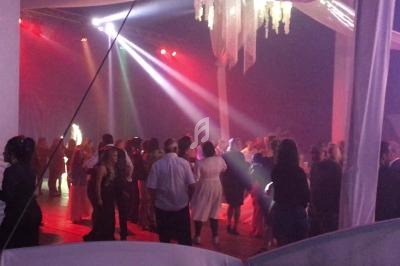 Groupe de personnes dansant sous des éclairages colorés dans une salle décorée avec des tentures blanches.