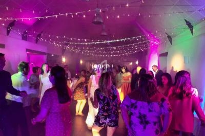 Des personnes dansent sous des guirlandes lumineuses dans une salle éclairée par des lumières colorées.