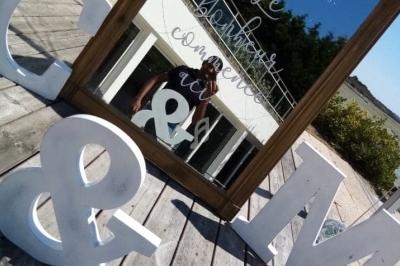 Un miroir avec une inscription réfléchissant une personne, entouré de grandes lettres décoratives sur une terrasse en bois.