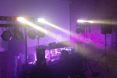 Équipement de sonorisation et éclairage installé dans une salle sombre avec des projecteurs lumineux violets.