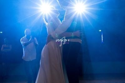 Un couple danse sous des projecteurs lumineux dans une ambiance tamisée sur une piste de danse.