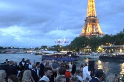 Groupe de personnes rassemblées en soirée près de la Seine, avec la Tour Eiffel illuminée en arrière-plan.