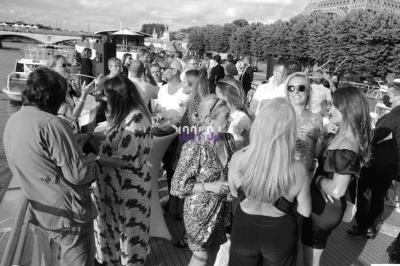Groupe de personnes discutant et profitant d'un événement en plein air sur un bateau près de la Tour Eiffel.