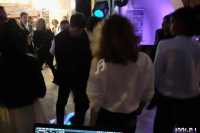 Des personnes dansent dans une ambiance festive avec éclairages colorés, vue partielle d'une table de mixage au premier plan.