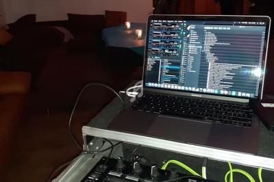 Poste de DJ avec une console de mixage et un ordinateur portable, dans un espace intérieur avec des personnes en arrière…