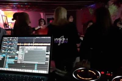 Personnes dansant dans une ambiance festive avec une table de mixage et un écran d'ordinateur au premier plan.