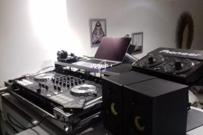 Équipement de DJ avec table de mixage, platines, haut-parleurs et ordinateur portable dans une pièce.