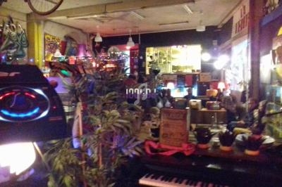 Intérieur d'un café rétro avec décoration éclectique, plantes, piano et éclairage tamisé.