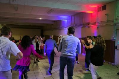 Des personnes dansent en groupe dans une salle éclairée par des lumières colorées.