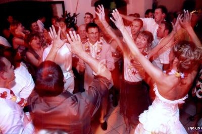 Groupe de personnes dansant et célébrant dans une ambiance festive avec des décorations tropicales.