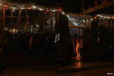 Façade vitrée d'un bâtiment éclairé par des guirlandes lumineuses, laissant entrevoir des silhouettes à l'intérieur.
