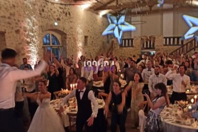 Salle de réception en pierre illuminée, remplie d'invités célébrant un événement festif avec musique et danse.