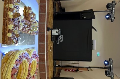 Gâteau décoré en gros plan sur une table devant un équipement de sonorisation et d'éclairage dans une salle.