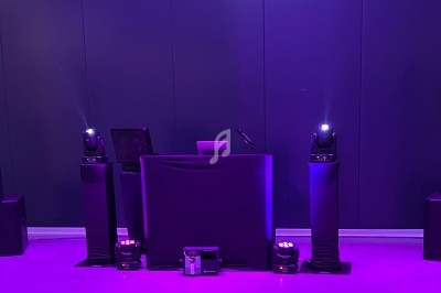 Installation de matériel de sonorisation et d'éclairage avec une table de mixage dans une ambiance lumineuse violette.
