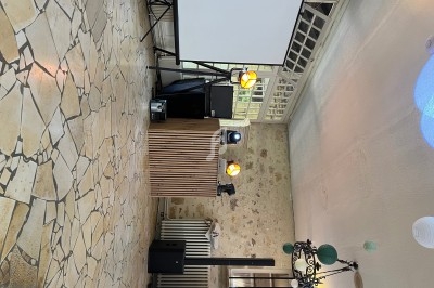 Console de DJ avec éclairage et équipement audio dans une salle au mur en pierre et sol en carrelage beige.