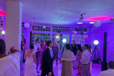 Personnes dansant et discutant dans une salle éclairée par des lumières colorées, décorée de lanternes suspendues.
