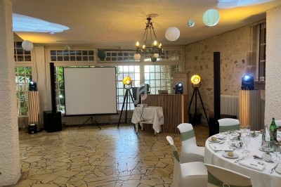 Salle de réception décorée avec des lanternes suspendues, un écran de projection et des équipements d'éclairage.