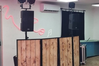 Installation de matériel de sonorisation et d'éclairage dans une salle avec un comptoir en bois et un néon mural.