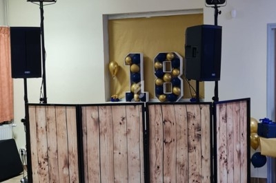 Installation de matériel de sonorisation et d'éclairage devant une décoration avec le chiffre 18 en ballons.