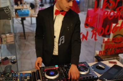 Un homme en costume avec un nœud papillon rouge utilise une table de mixage dans un espace intérieur.