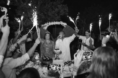 Des personnes entourent un couple célébrant un événement festif avec des cierges magiques autour d'une table décorée.