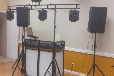 Équipement de sonorisation et éclairage installé dans une salle, comprenant enceintes, projecteurs et table de mixage.