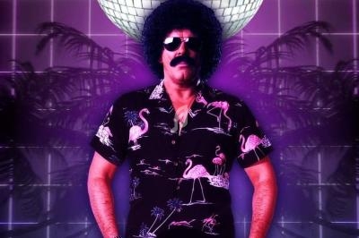 Homme en chemise à motifs et perruque afro tenant un vinyle, devant une boule disco et un décor rétro lumineux.