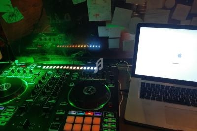 Console de mixage éclairée en vert à côté d'un ordinateur portable affichant un écran de démarrage Apple.