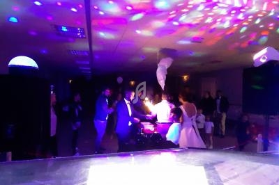 Des invités dansent sous des lumières colorées dans une salle de fête sombre.