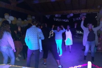 Des personnes dansent sous un abri décoré de ballons et guirlandes lumineuses lors d'une soirée festive.