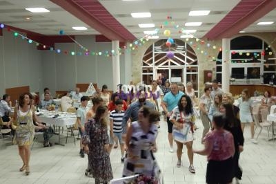 Des personnes dans une salle décorée avec des guirlandes colorées, participant à une fête ou un événement convivial.