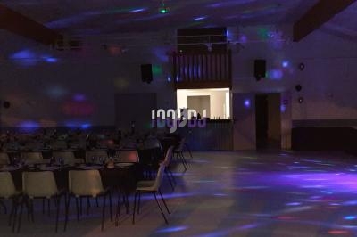 Salle de réception sombre avec tables dressées et éclairages colorés projetés sur les murs et le sol.