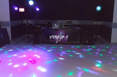 Jeu de lumières colorées projetées sur une piste de danse, avec une table de mixage en arrière-plan.