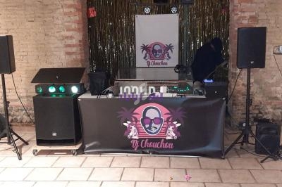 Installation de matériel de sonorisation et éclairage pour une prestation DJ dans une salle en briques apparentes.