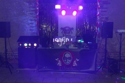 Installation de matériel de DJ avec éclairage coloré, enceintes et décorations dans une salle sombre.