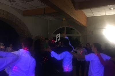 Groupe de personnes dansant et s'embrassant sous des lumières colorées dans une salle aux murs en pierre.