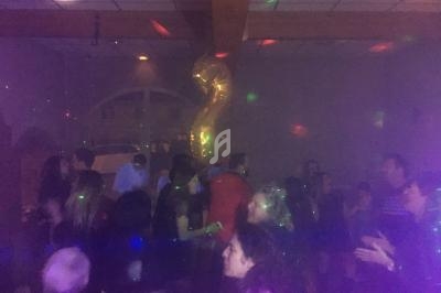 Groupe de personnes dans une salle sombre avec des lumières colorées et un ballon doré en forme de chiffre 2.