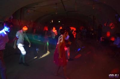 Des personnes dansent sous des lumières colorées dans une salle sombre, créant une ambiance festive.