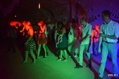 Personnes dansant dans une salle sombre éclairée par des lumières colorées, ambiance festive.