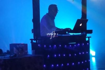 Un DJ mixant sur une scène éclairée par des lumières bleues et des projecteurs colorés.