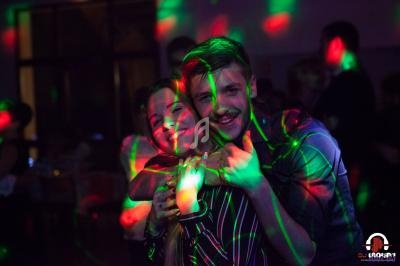 Un couple souriant dans une ambiance festive avec des lumières colorées projetées autour d'eux.