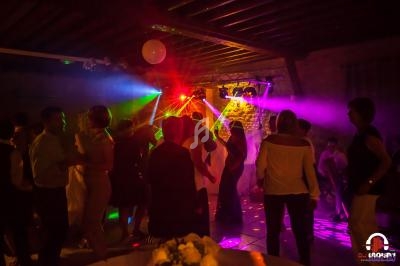 Groupe de personnes dansant sous des jeux de lumière colorés dans une salle avec un plafond en bois.