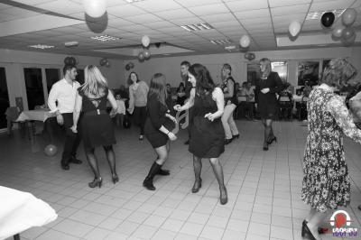 Des personnes dansent dans une salle décorée de ballons, lors d'un événement festif en intérieur.