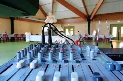 Table de mixage audio en gros plan dans une salle de réception décorée avec des ballons et des tables dressées.