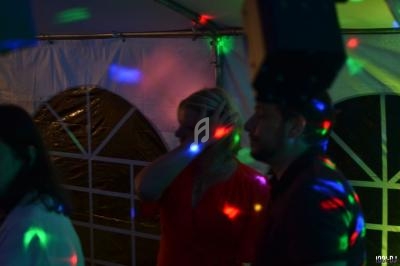 Personnes dans une ambiance de fête avec éclairages colorés et jeux de lumière dans une tente.