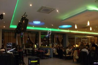 Salle de restaurant moderne avec éclairage coloré, tables occupées et équipement audio visible au premier plan.